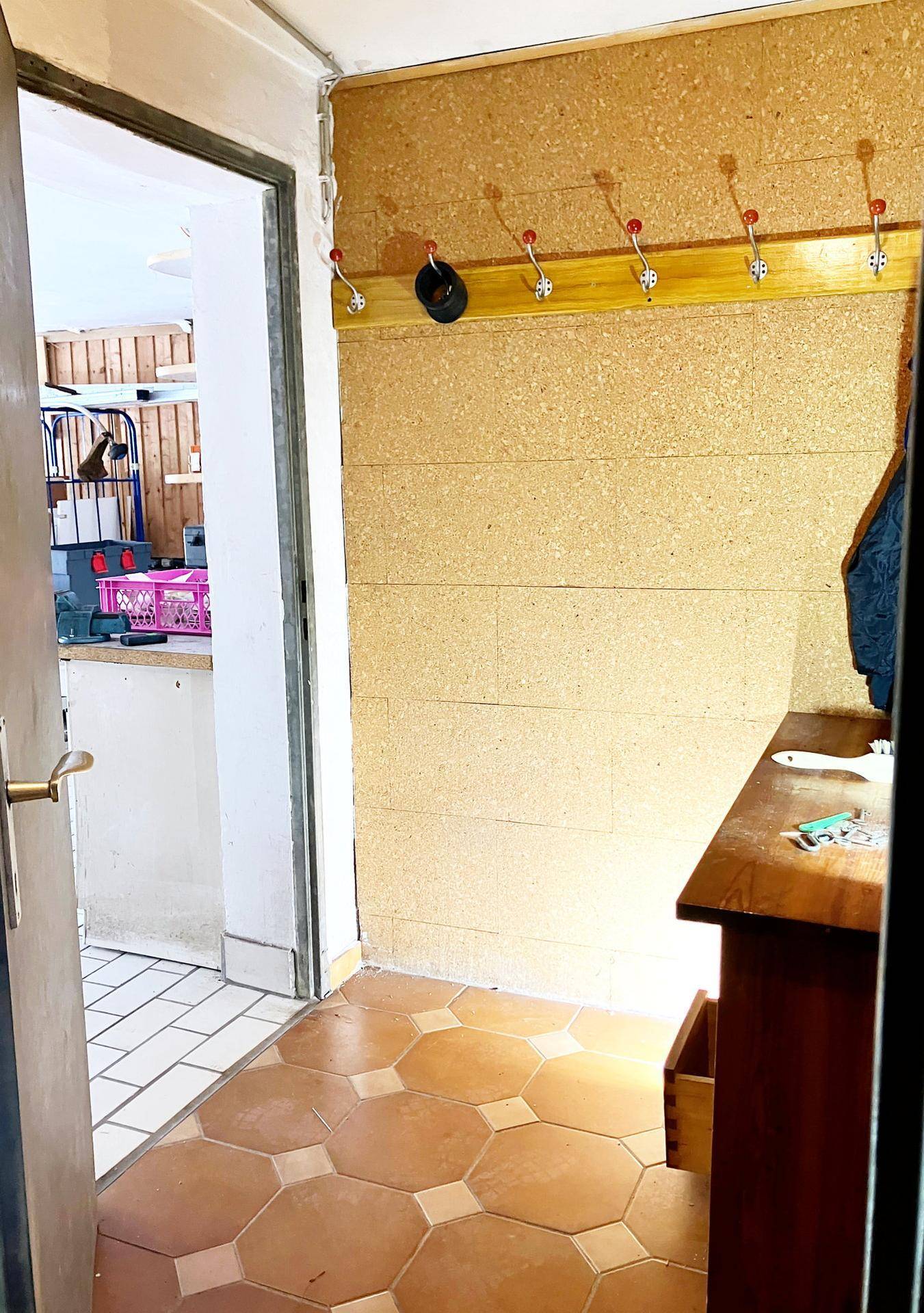 Eingangsbereich mit Korkwand, Garderobe und gefliestem Boden.