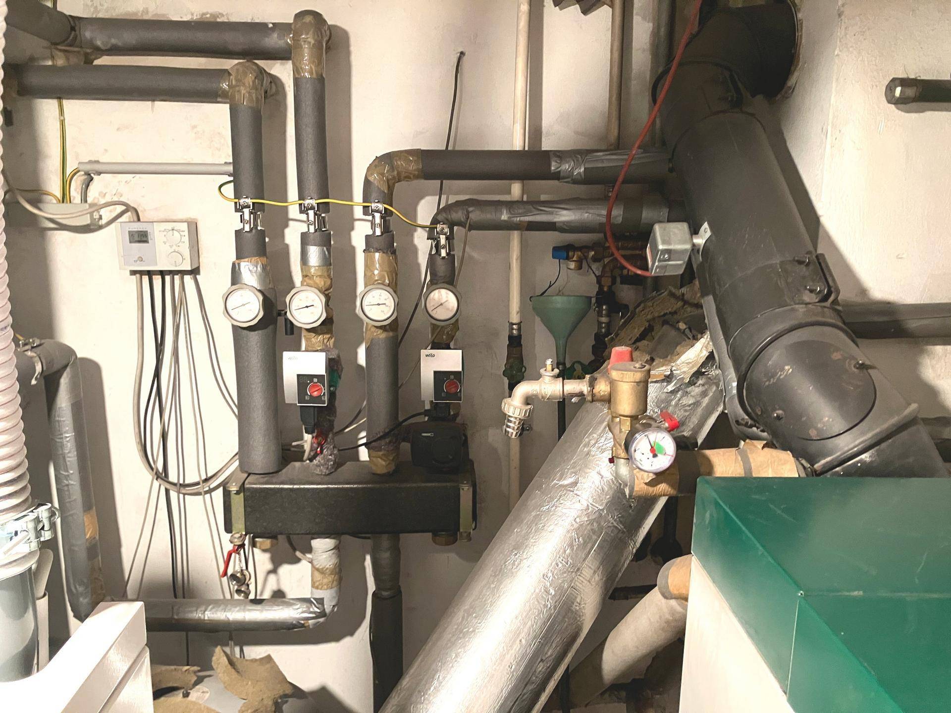 Heizungsraum mit komplexen Rohrleitungen und Messgeräten für die Gebäudetechnik.