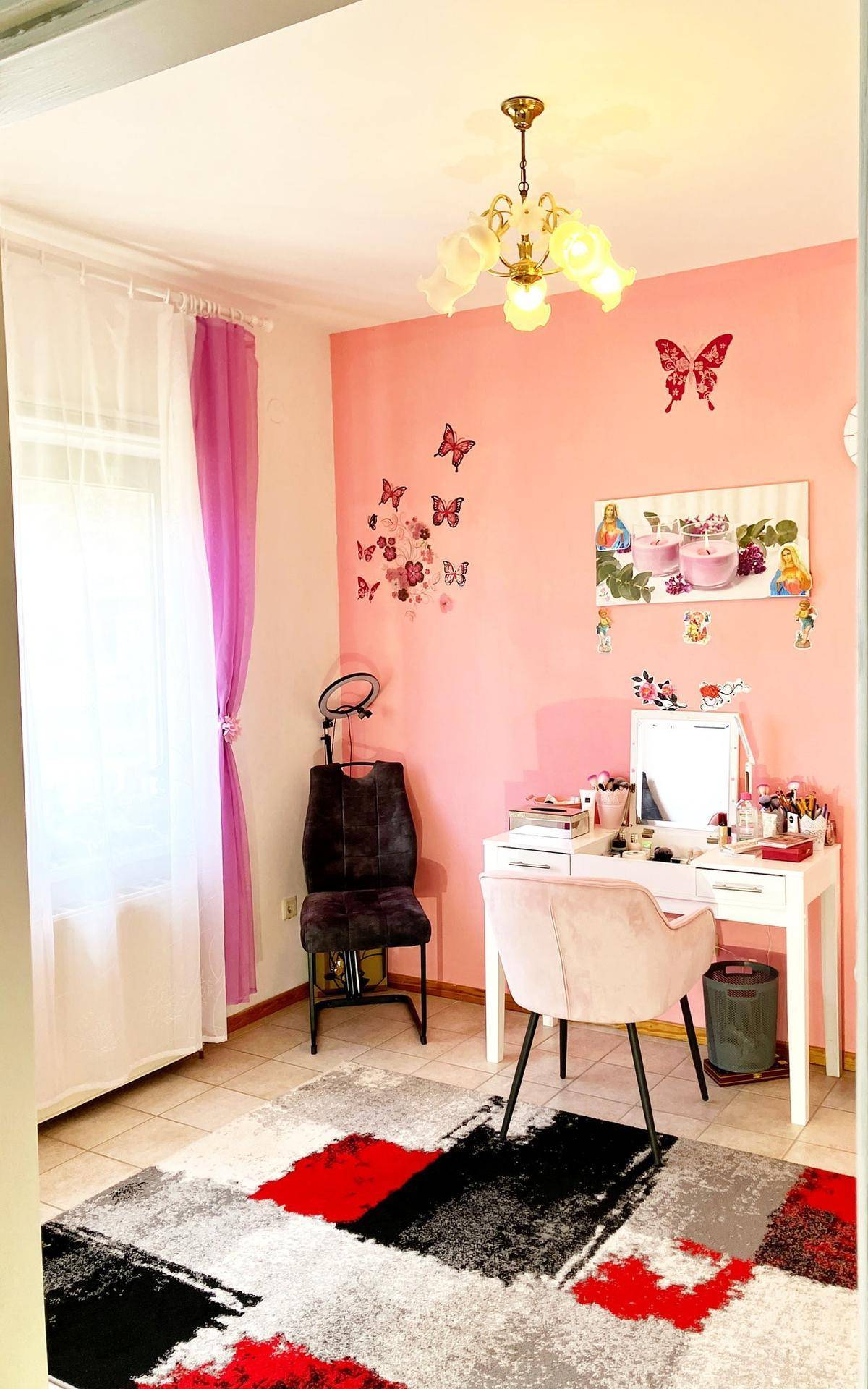Mädchenzimmer mit rosa Wänden, Schmetterlingsdekoration und einem Schminktisch.