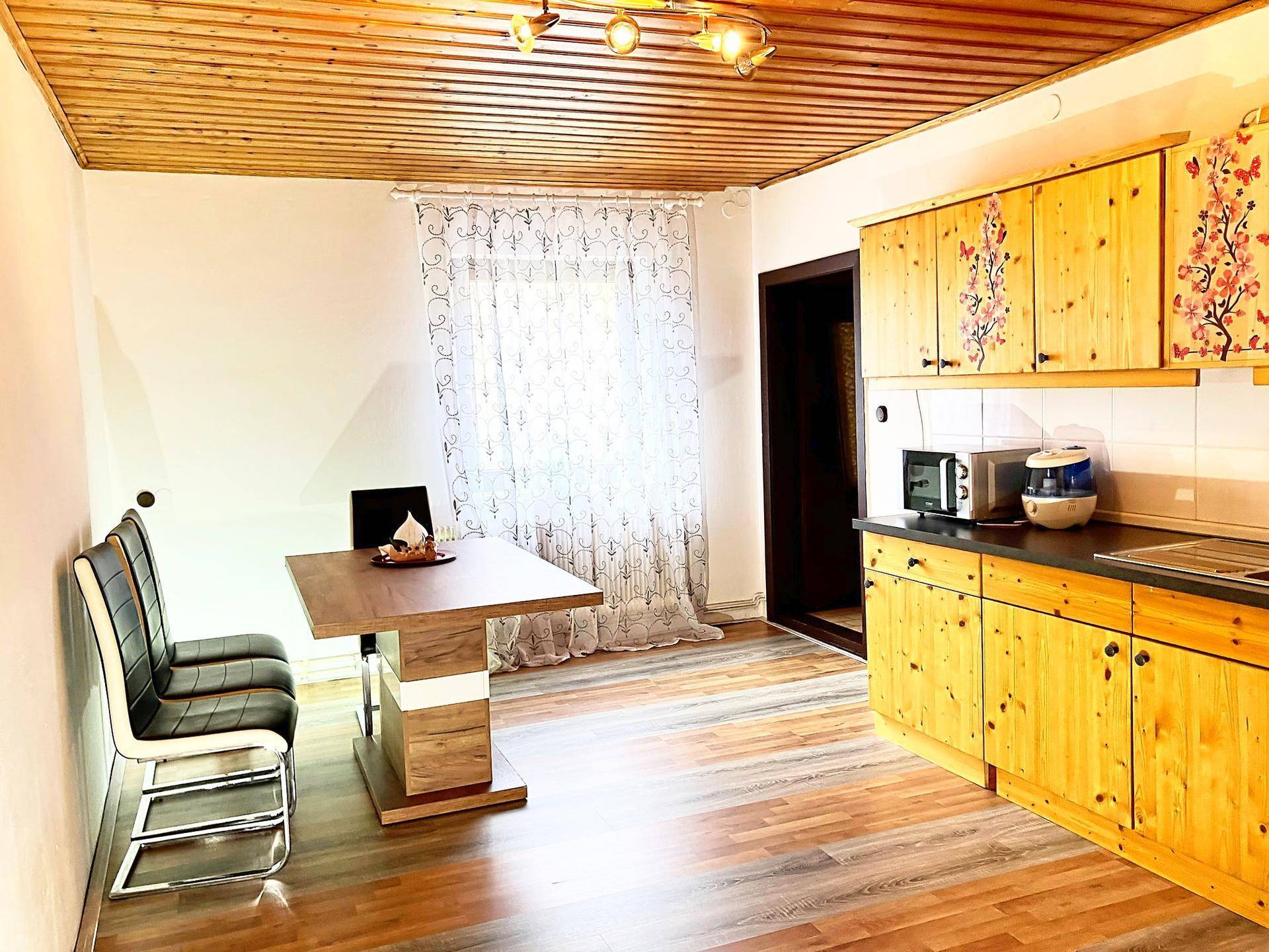 Rustikale Holzküche mit Essbereich, Holzdecke und Laminatboden.