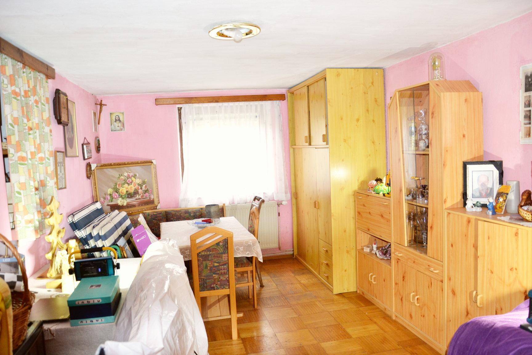 Geräumiger Wohn-Essbereich mit rosa Wänden, Holzmöbeln und Parkettboden.