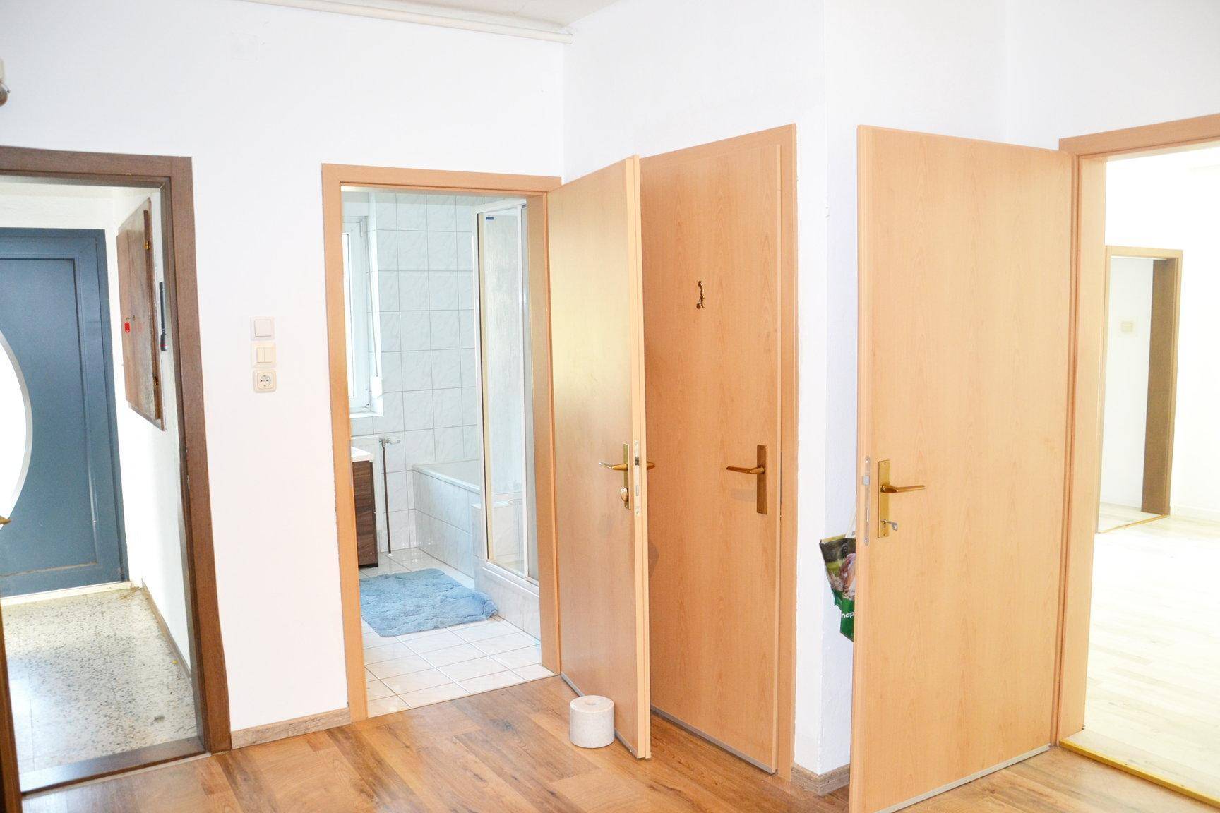 Heller Flur mit Holzböden und mehreren Türen, die zu verschiedenen Räumen führen.