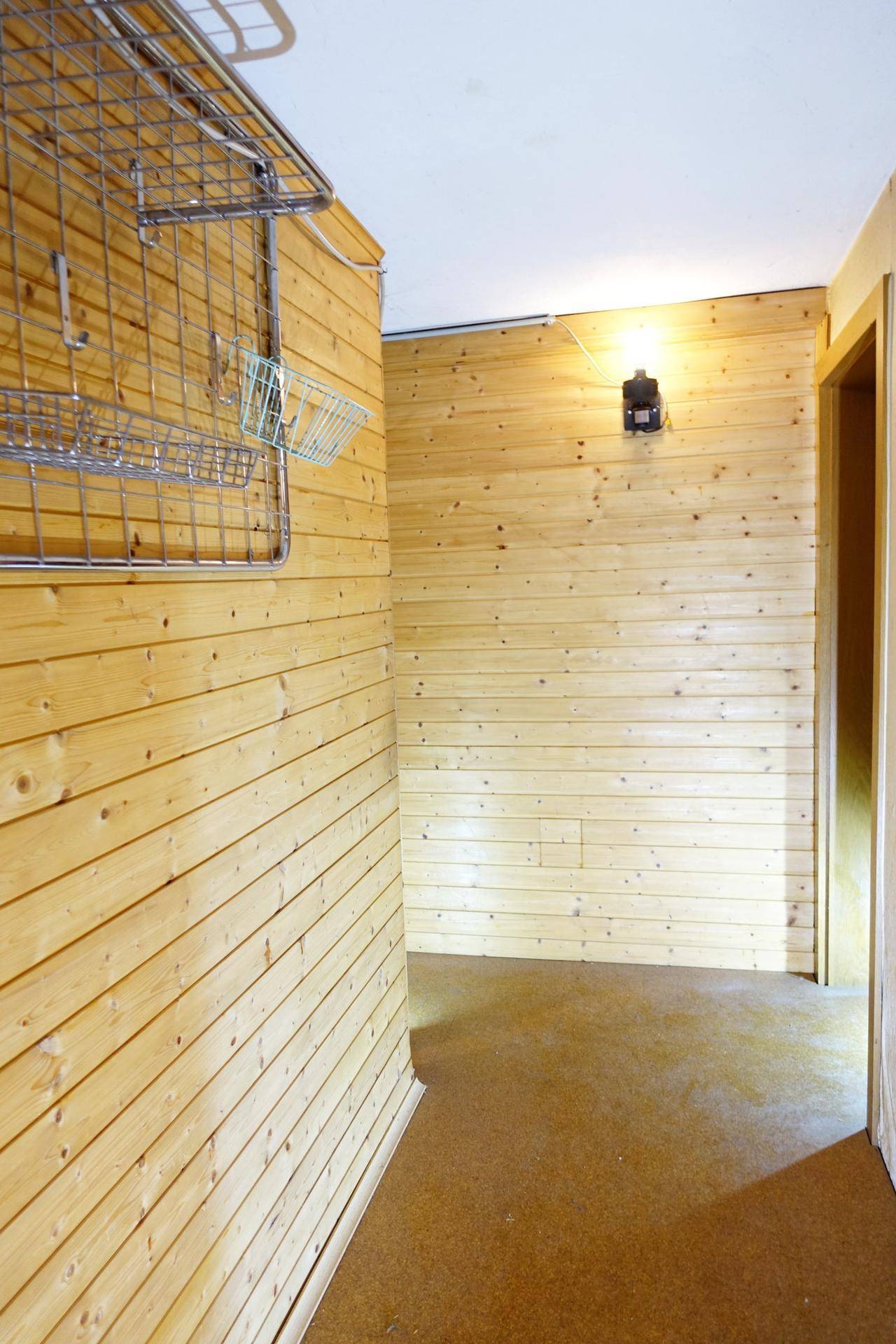 Flur mit Holzverkleidung und einem praktischen Metallregal an der Wand.