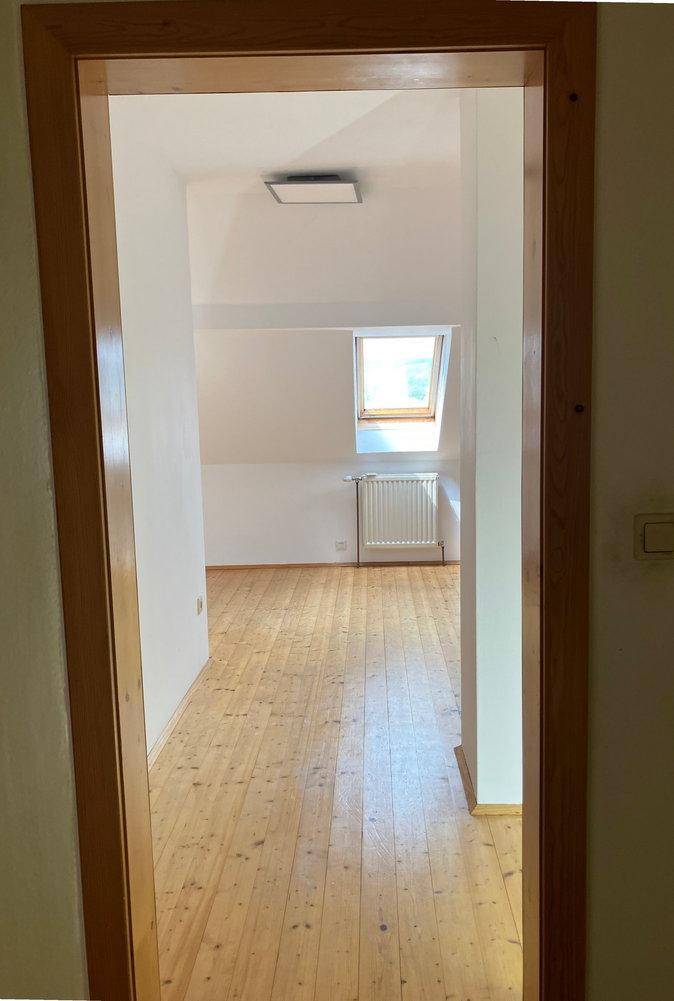 Heller Raum im Dachgeschoss mit Holzdielenboden und Dachfenster.