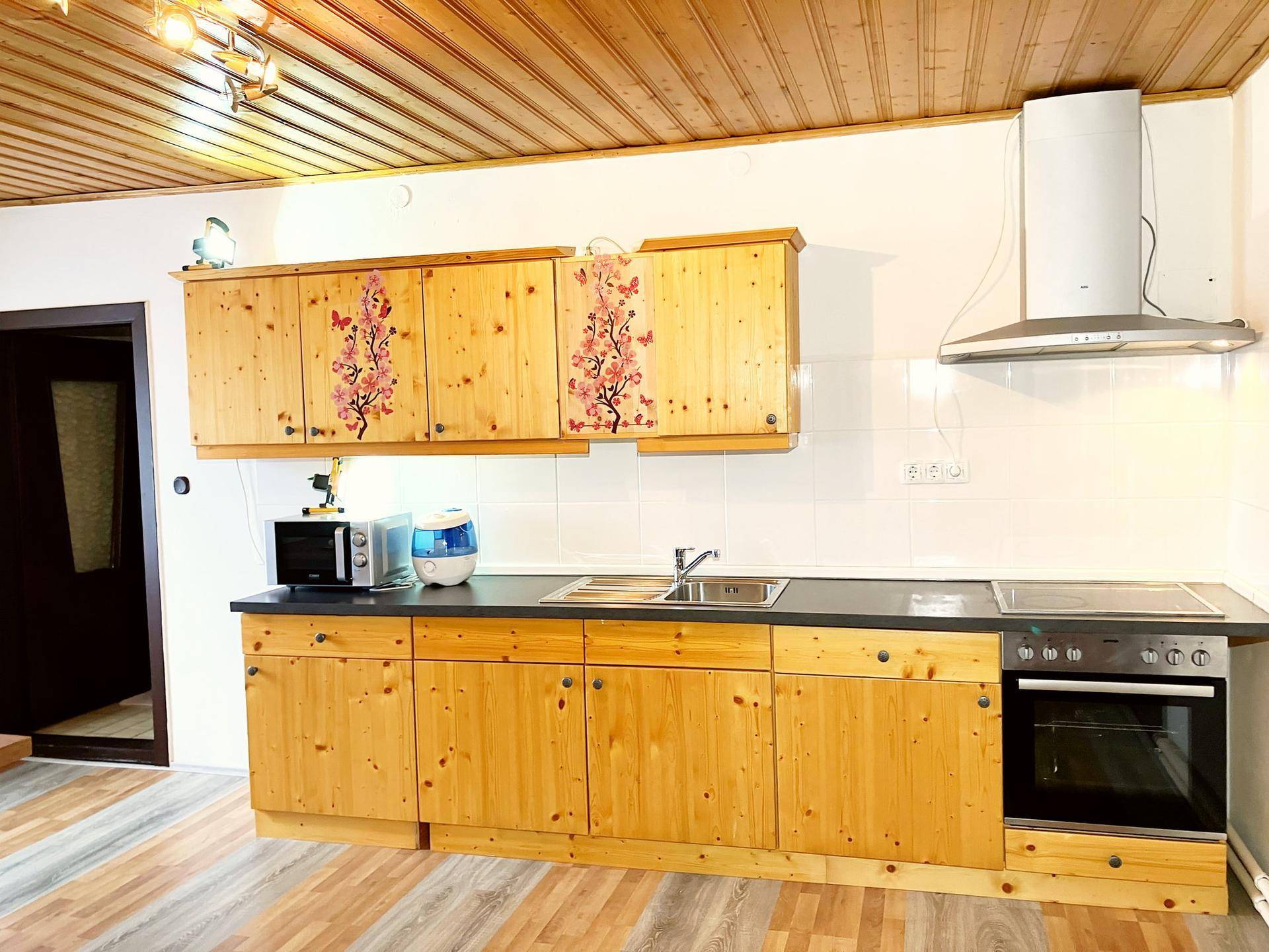Küche mit Holzschränken, Dunstabzugshaube und integriertem Backofen.