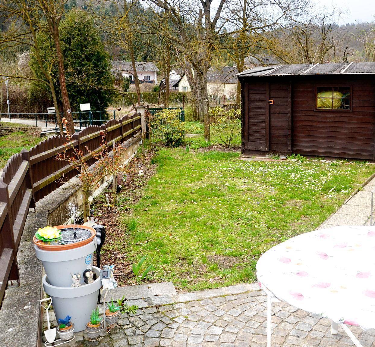 Grüner Gartenbereich mit Rasenfläche, Holzschuppen und Zaun, ideal für Entspannung im Freien.