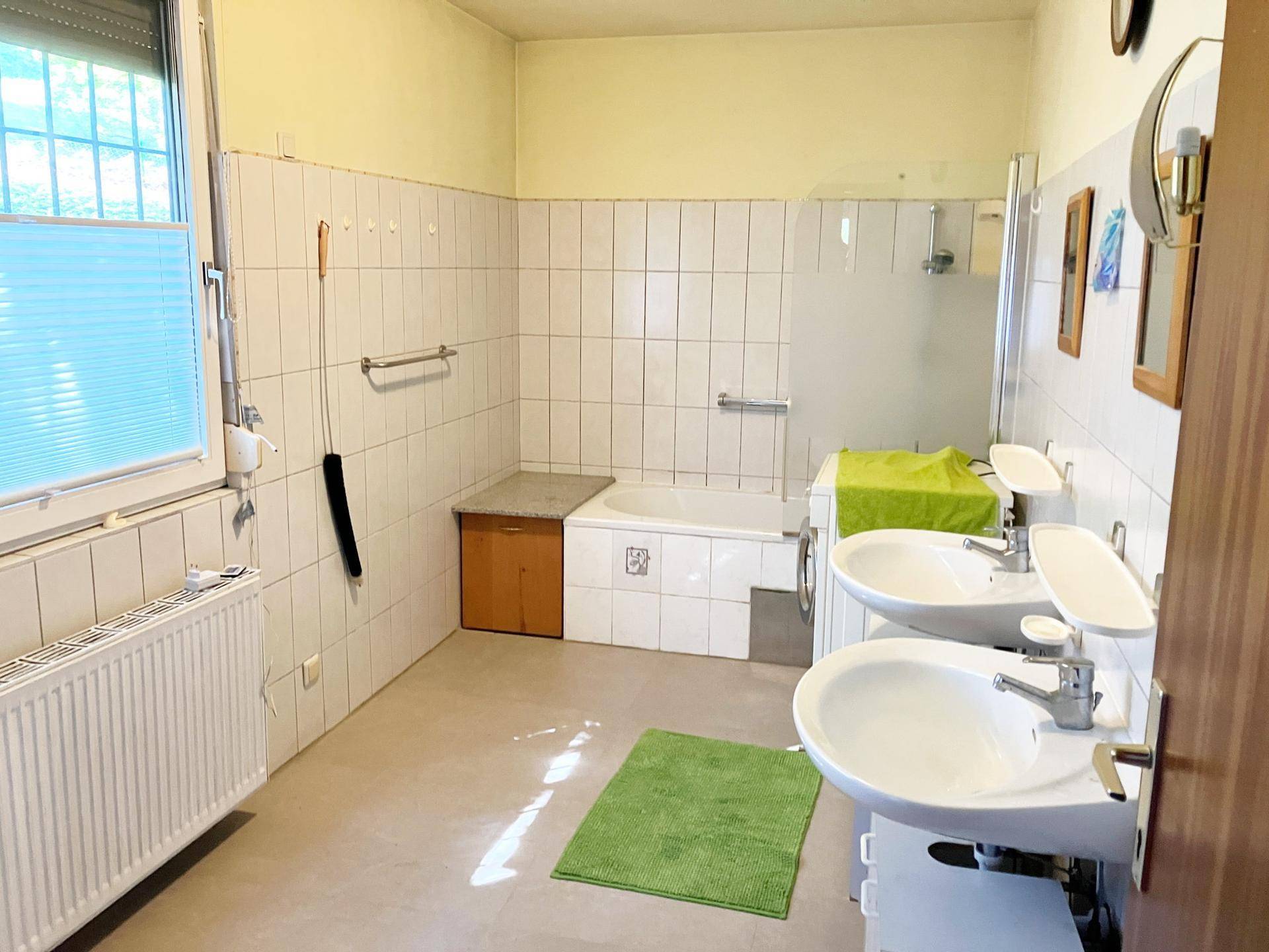 Geräumiges Badezimmer mit Doppelwaschbecken, Badewanne und Fenster.