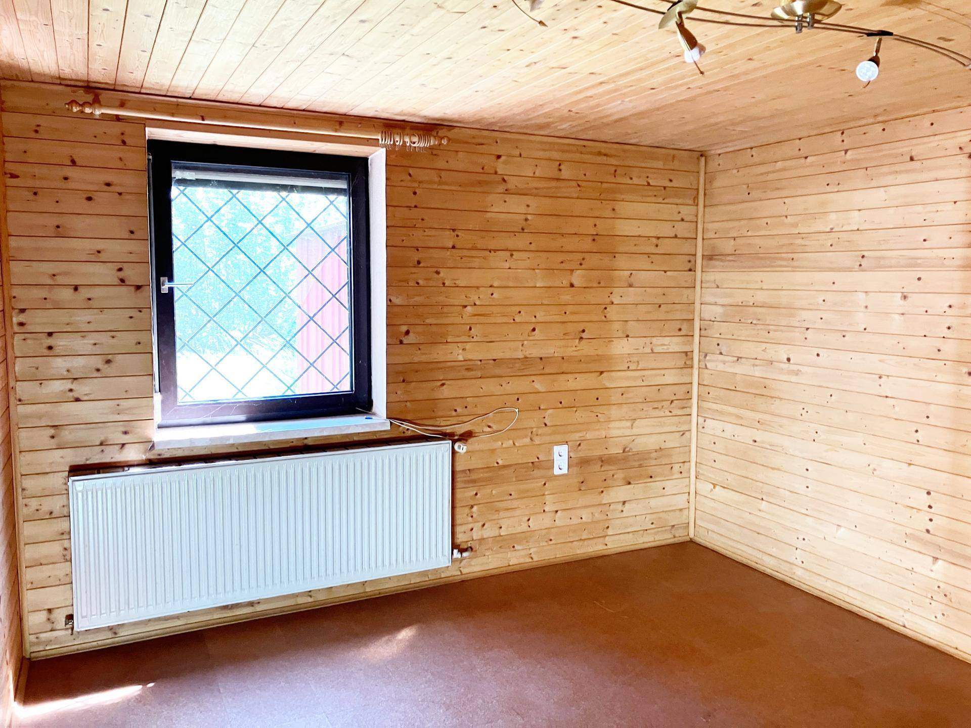 Gemütlicher Raum mit Holzverkleidung an Wänden und Decke, ausgestattet mit Heizkörper.