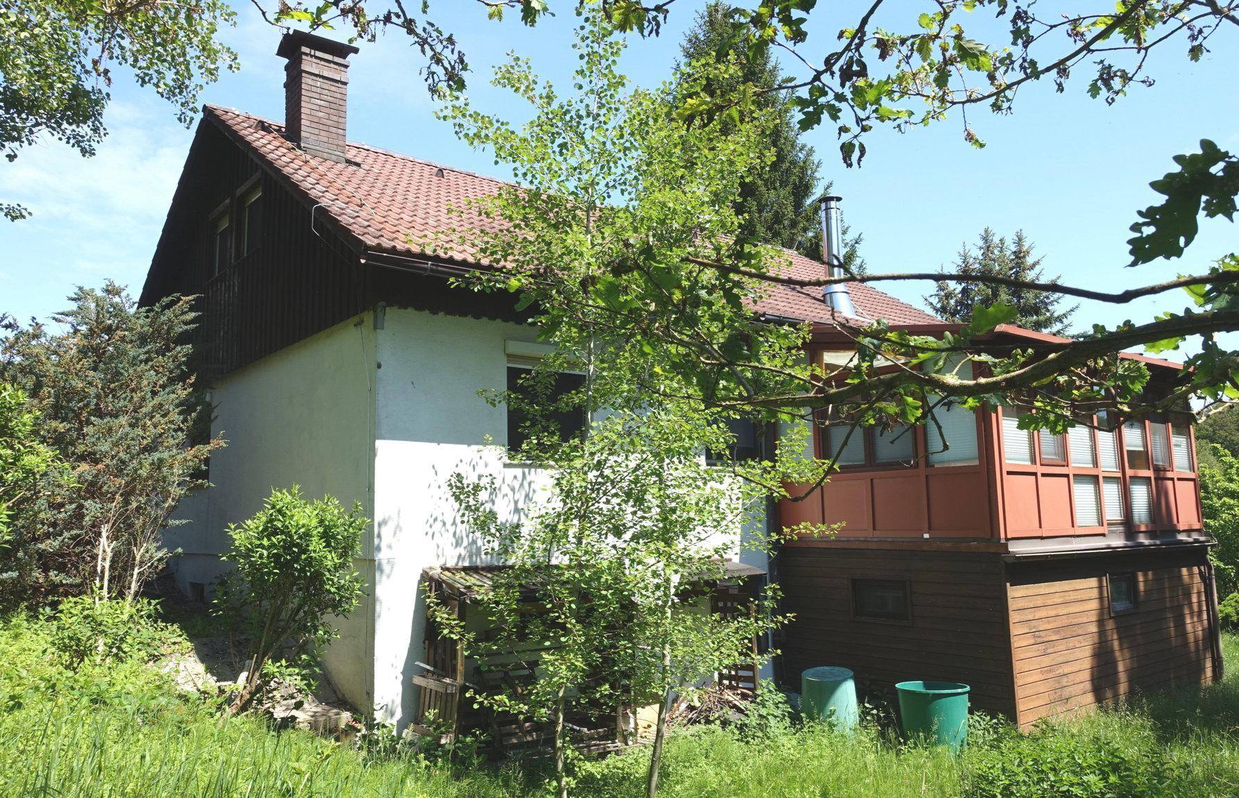 Ansicht des Hauses von einer anderen Seite, umgeben von üppiger Vegetation und Bäumen.