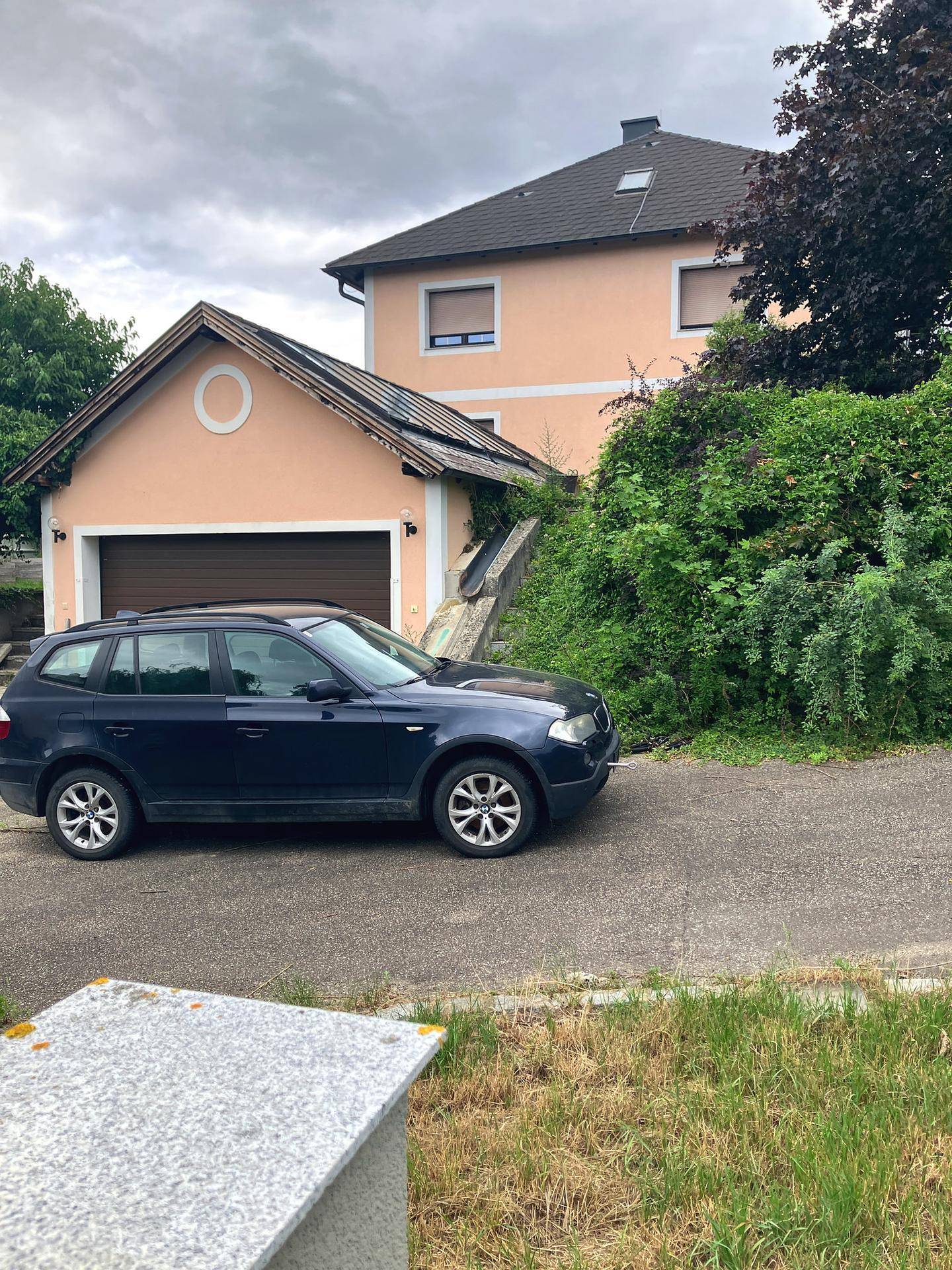 Einfamilienhaus mit integrierter Garage und gepflegter Zufahrt unter bewölktem Himmel.