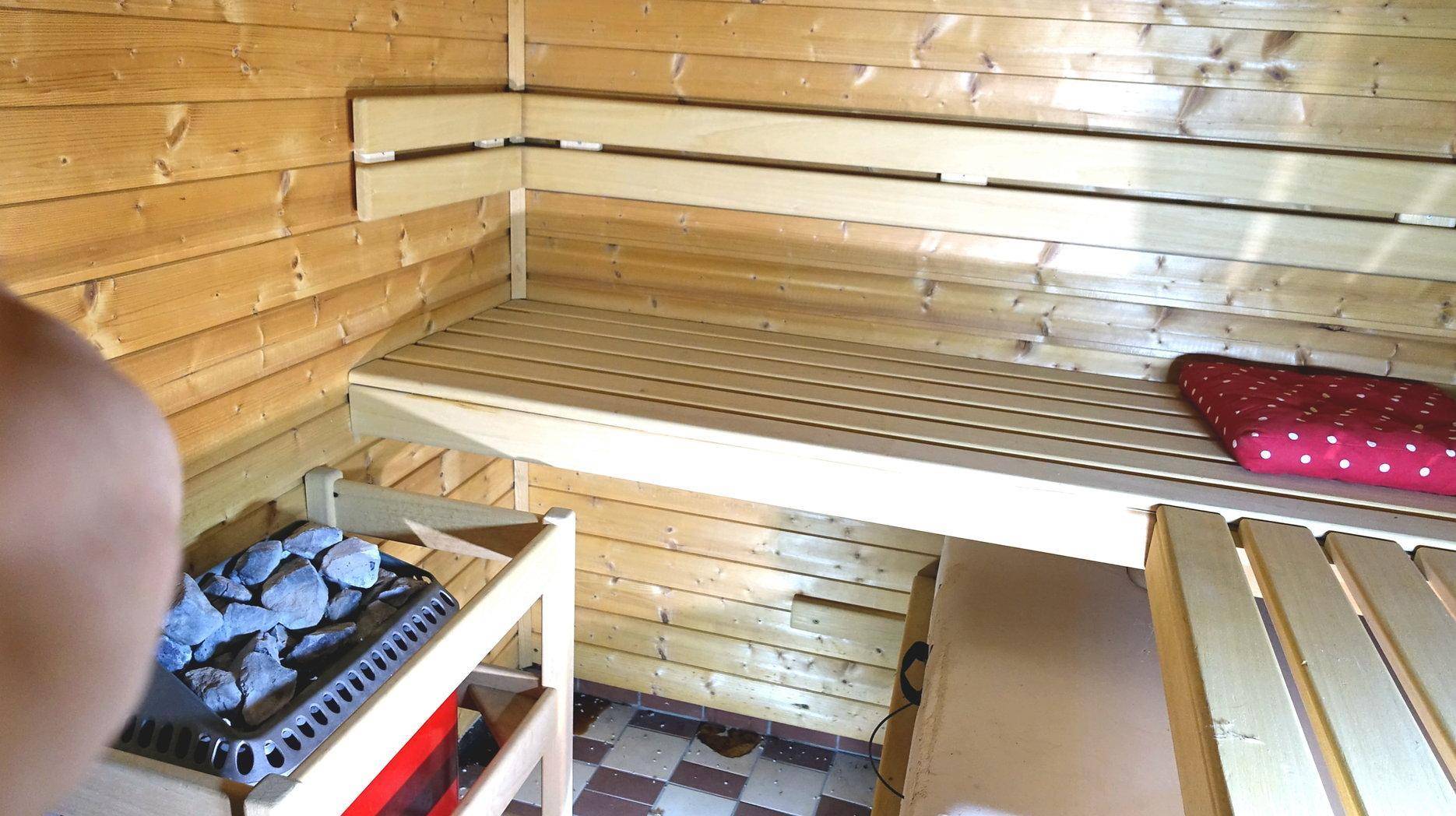 Detailansicht des Saunaofens mit Steinen und Holzbänken in der Sauna.