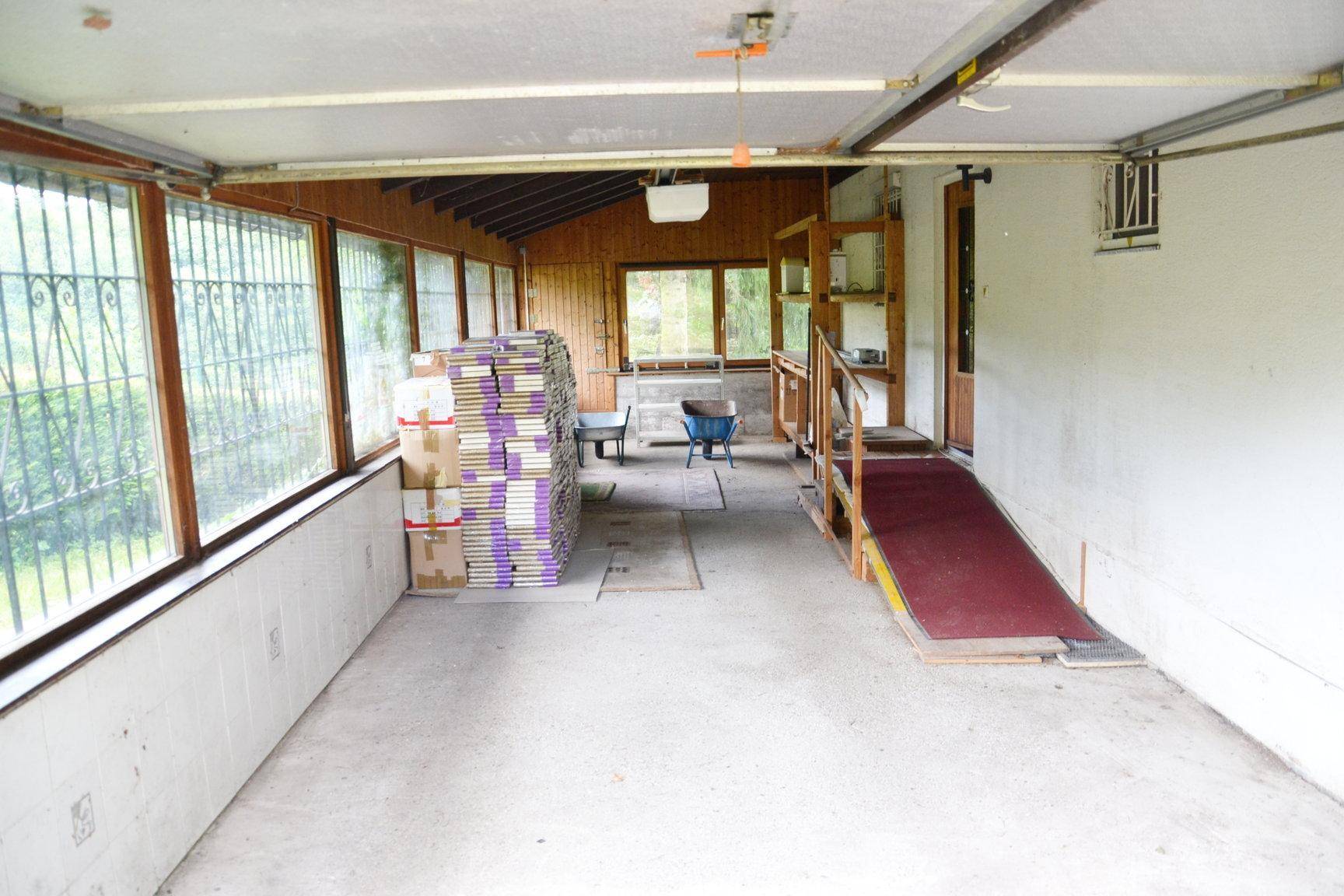 Großer Raum, möglicherweise eine Garage oder Werkstatt, mit einer Rampe und vergitterten Fenstern.