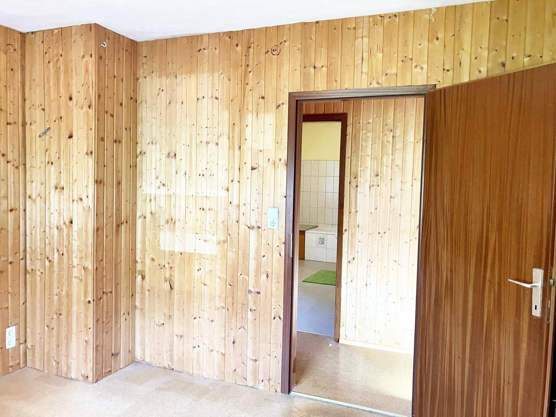 Schlafzimmer mit Holzvertäfelung und Zugang zu einem Badezimmer.