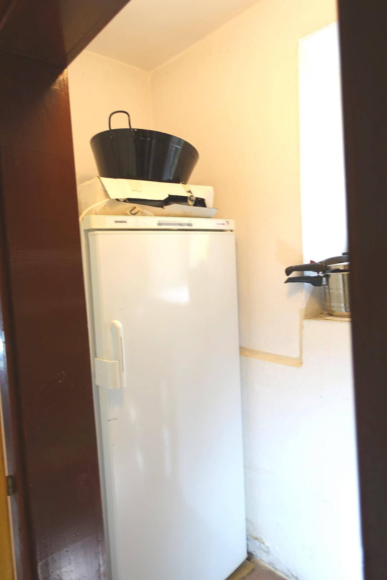 Kleiner Abstellraum mit Kühlschrank und begrenztem Platz.