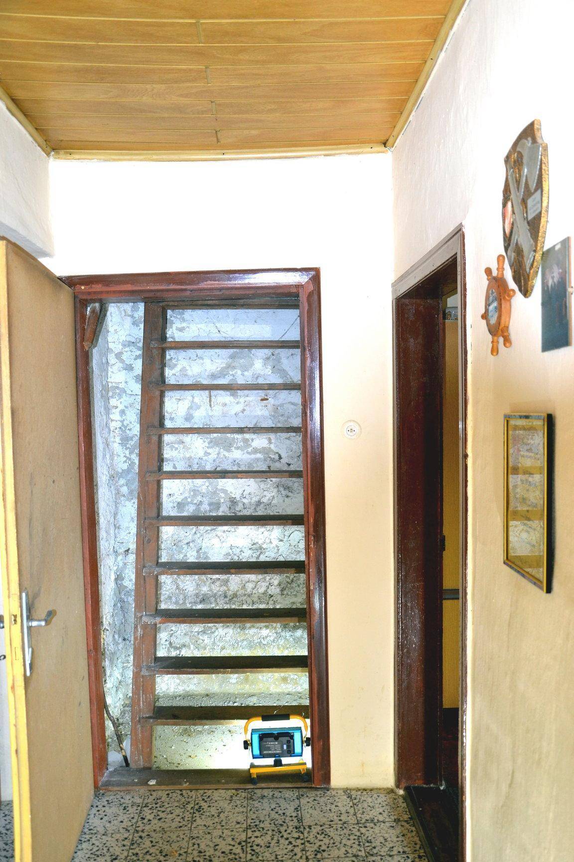 Flur mit Holztreppe, die in einen unfertigen Bereich führt.