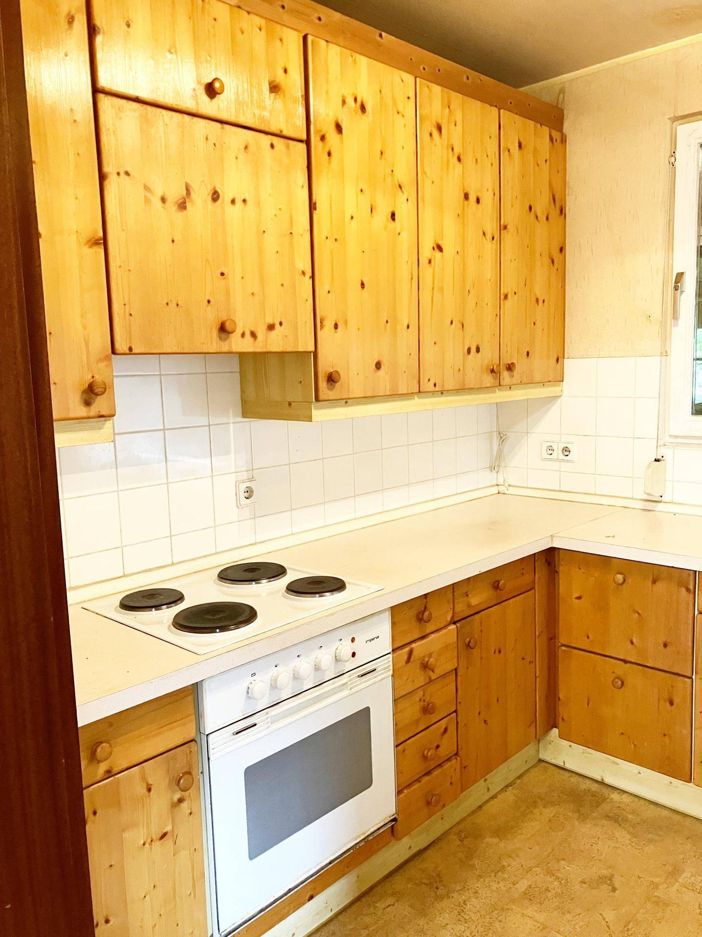 Küche im Landhausstil mit Holzschränken, weißen Fliesen und Elektroherd.