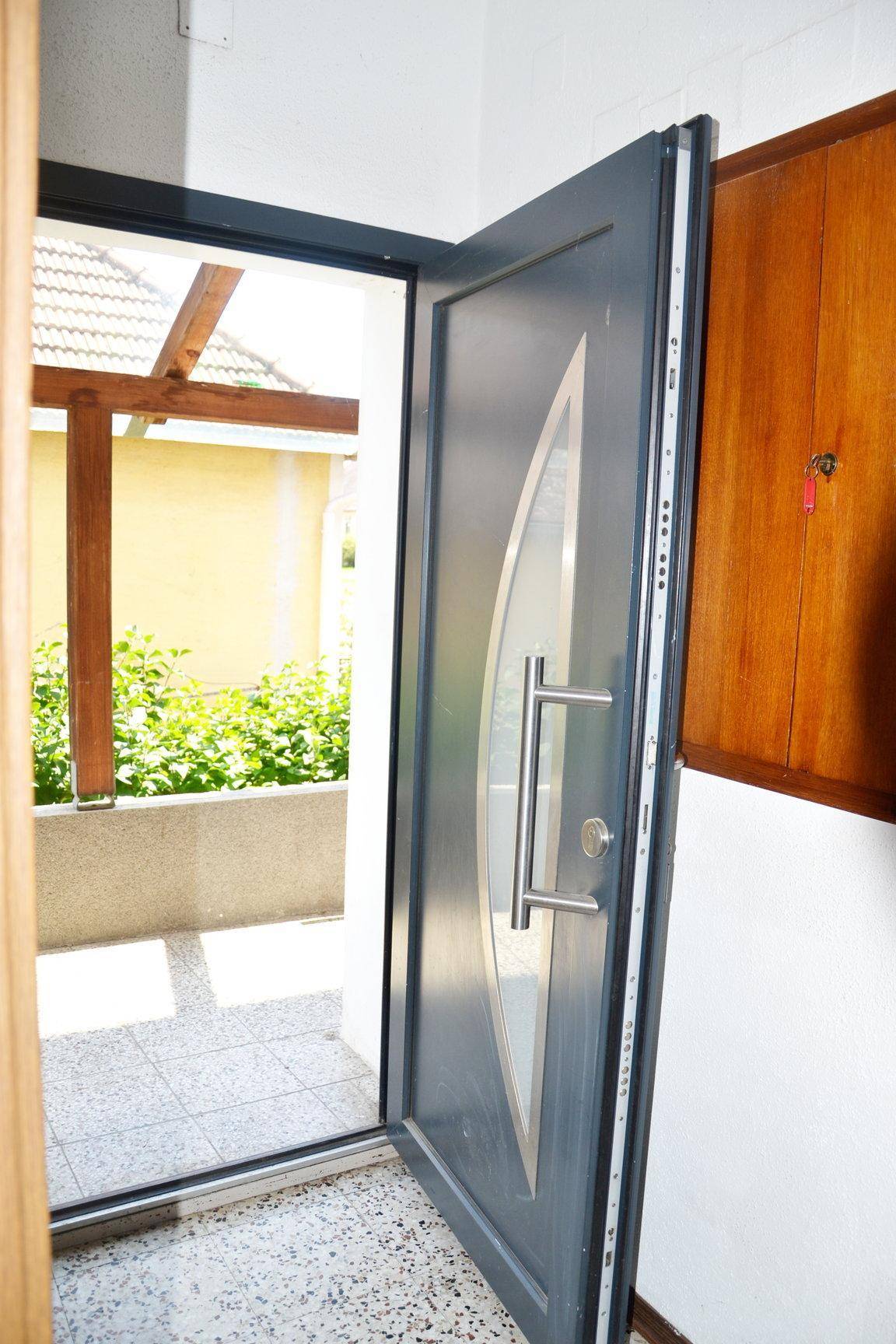 Offene Eingangstür mit modernem Design, die den Blick auf den Außenbereich freigibt.