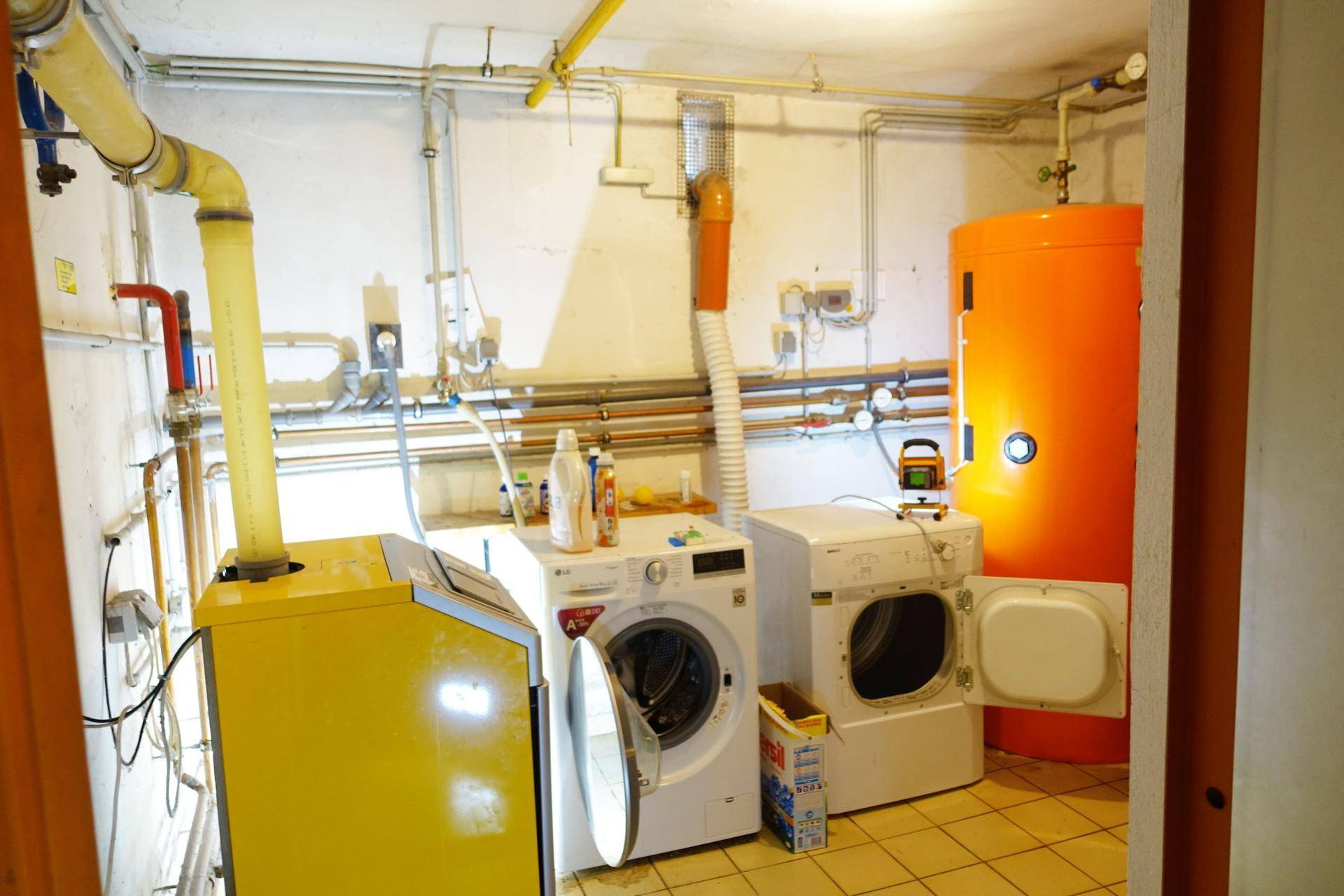 Waschküche mit Waschmaschine, Trockner und Warmwasserspeicher.