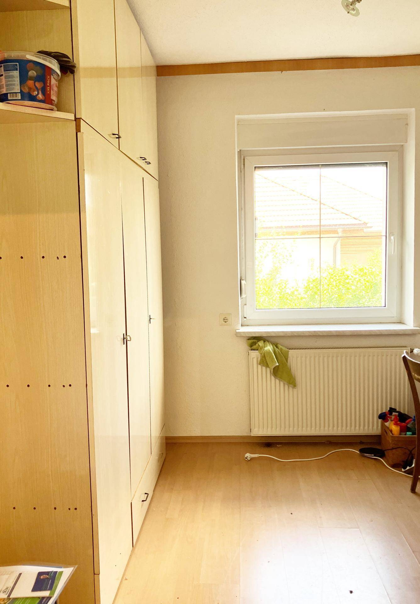 Heller Raum mit Holzboden, Fenster und Heizkörper, ausgestattet mit hellen Holzschränken.