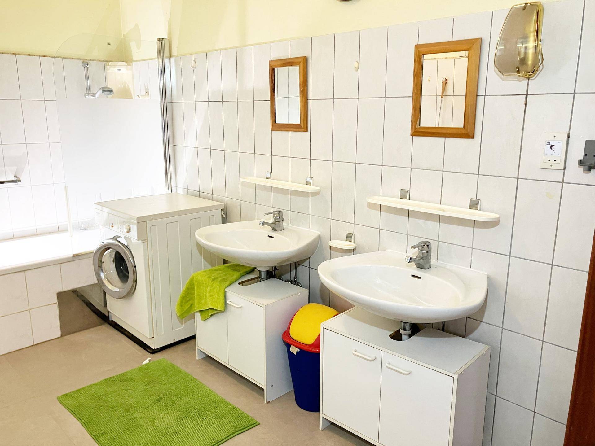 Badezimmer mit Doppelwaschbecken, Badewanne und Waschmaschine.