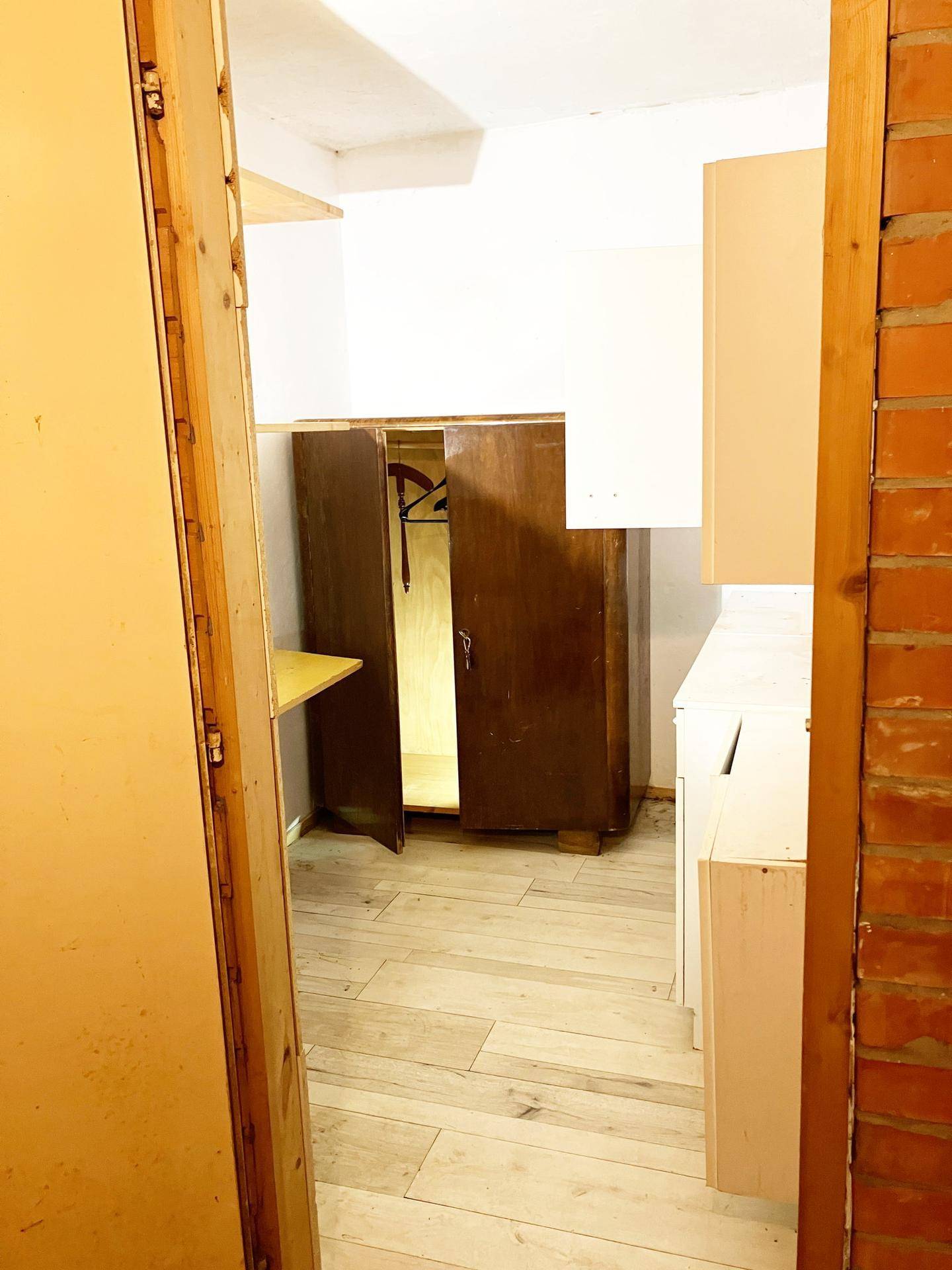 Abstellraum mit Holzboden, Schrank und Regalen.