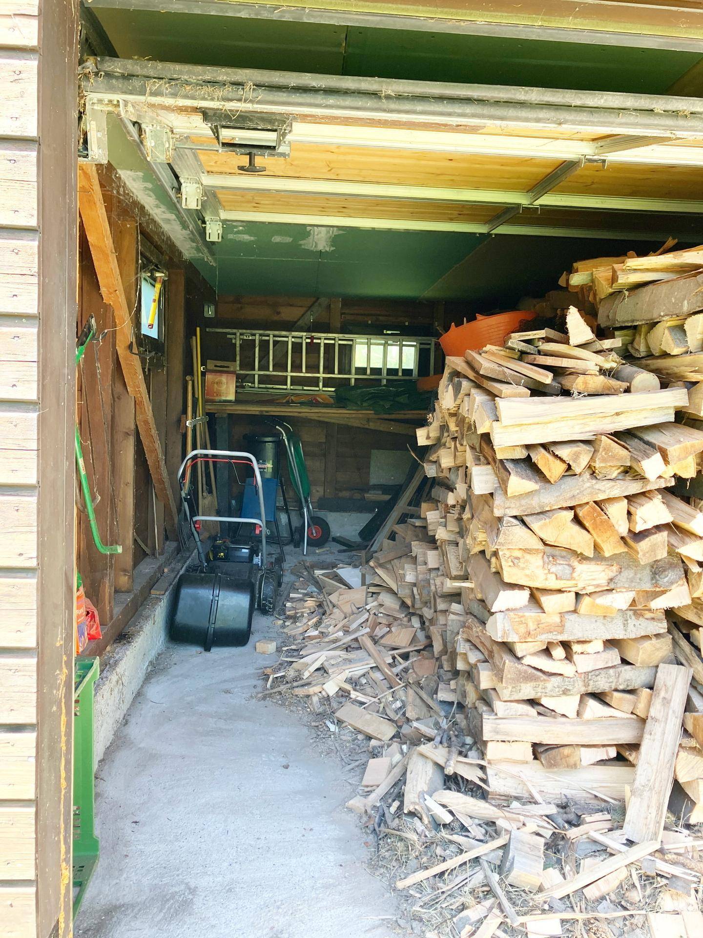 Innenansicht einer Garage oder eines Lagerraums mit einem großen Stapel Brennholz.