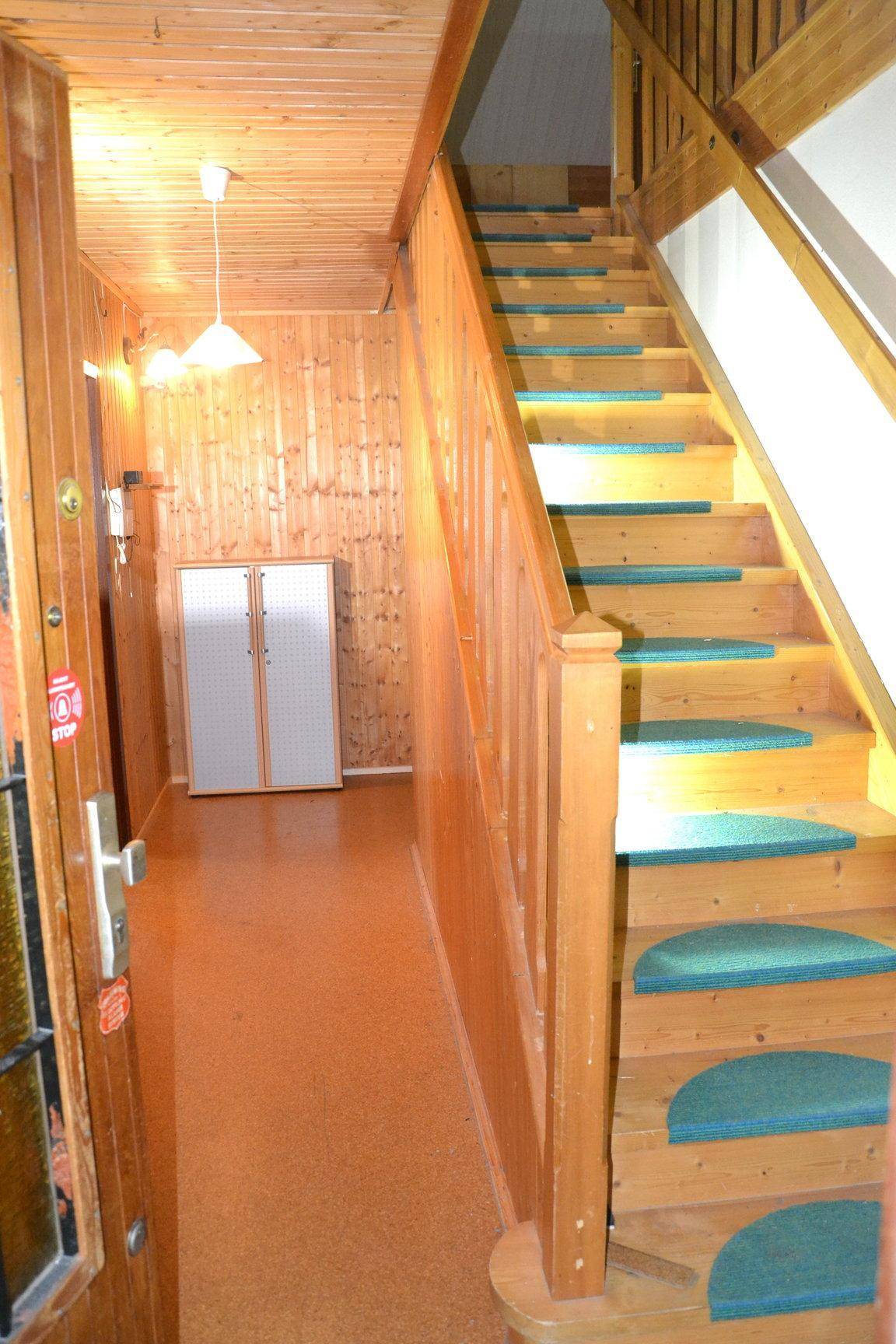 Flur mit Holztreppe und Holzvertäfelung, die den rustikalen Charme unterstreicht.