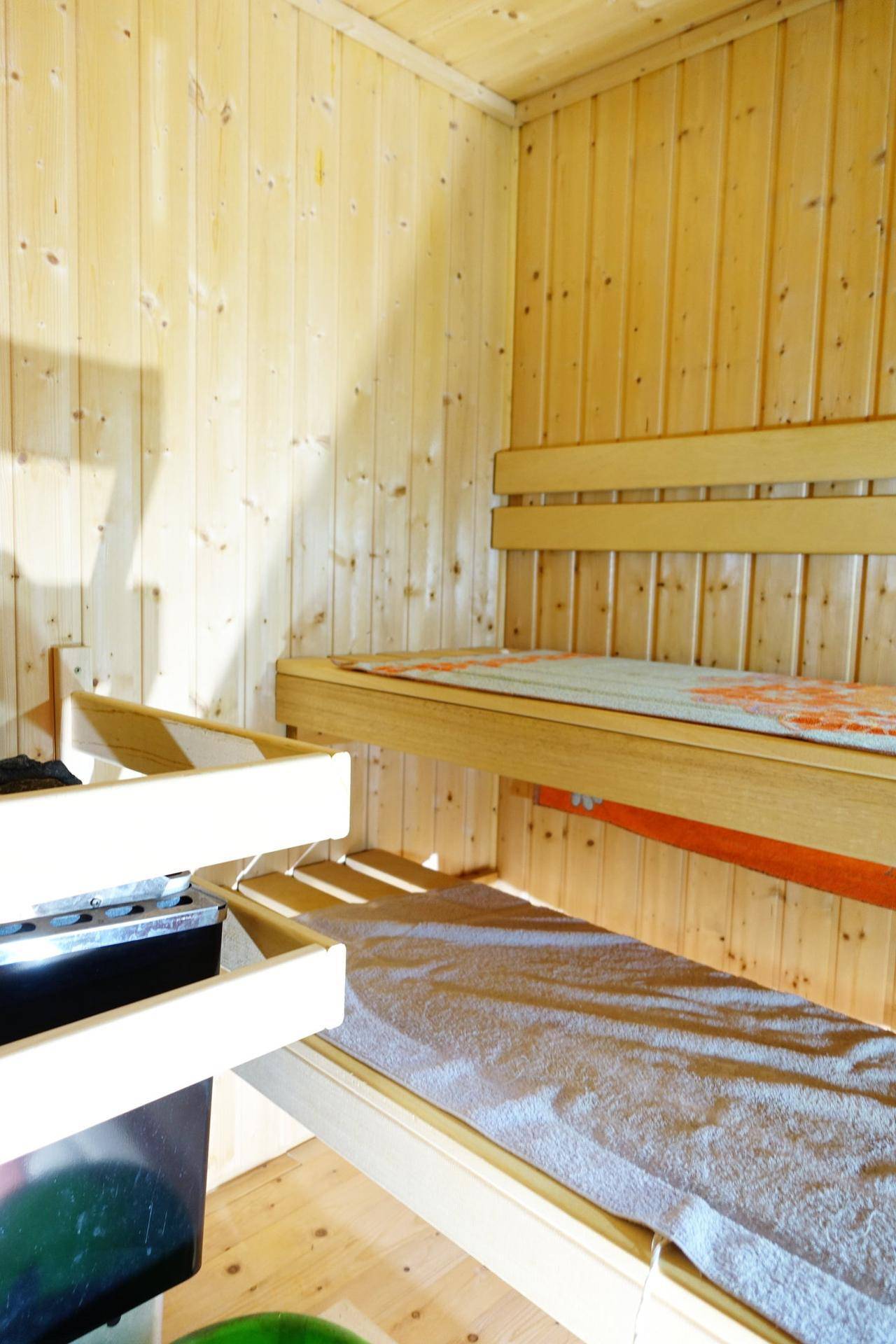 Detailansicht des Saunaofens und der Holzbänke in der traditionellen Sauna.