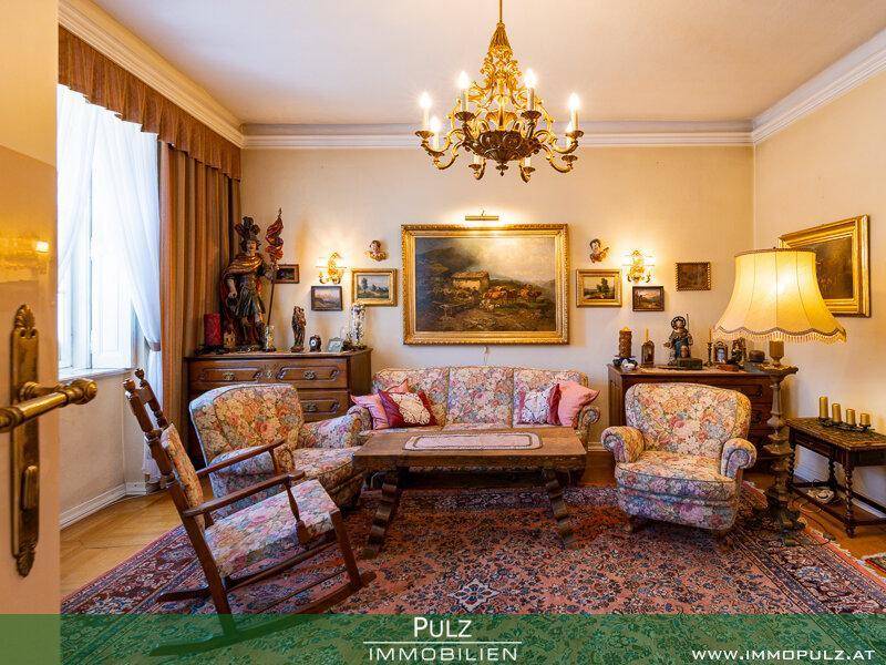 Gemütliches Wohnzimmer mit floral gemusterten Polstermöbeln und einem eleganten Kronleuchter.