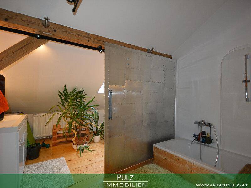 Modernes Badezimmer im Dachgeschoss mit Badewanne und Schiebetür aus Metall.