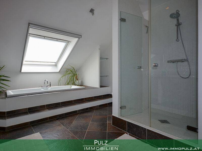 Modernes Badezimmer mit Badewanne, Dusche und Oberlicht für natürliches Licht.