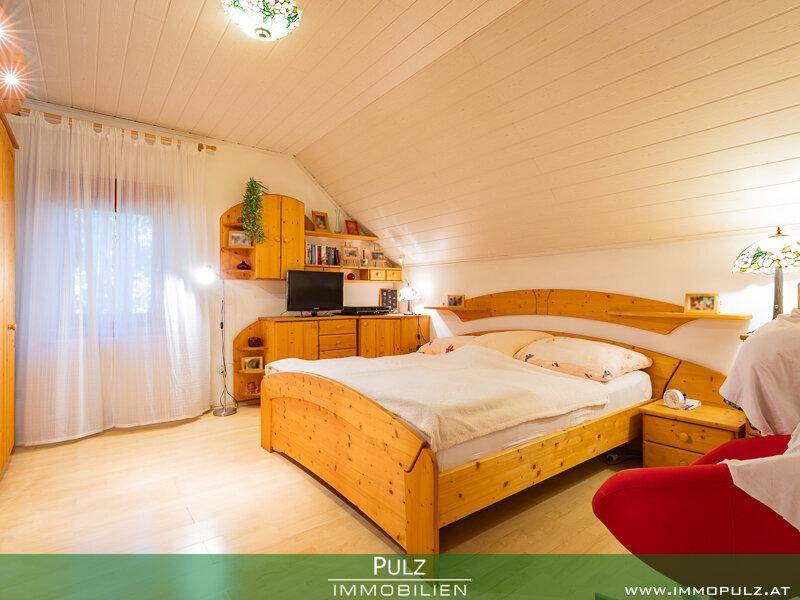 Gemütliches Schlafzimmer mit Holzbett, Dachschräge und hellem Laminatboden.
