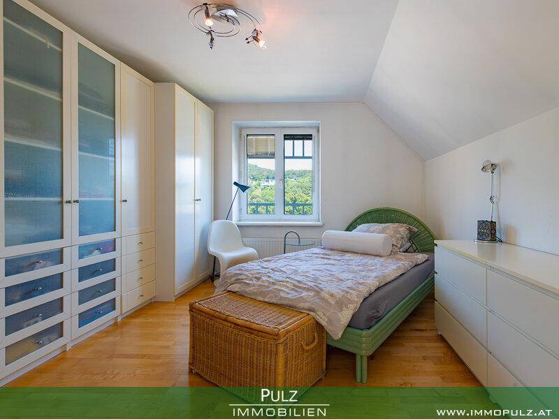 Helles Schlafzimmer mit Dachschräge, Einzelbett und praktischen Einbauschränken.