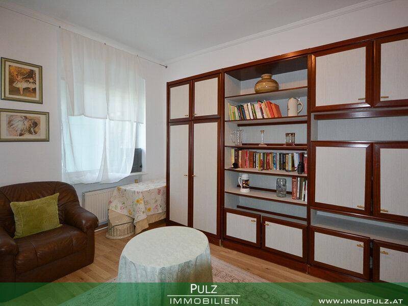 Wohnzimmer mit Holzboden und großer Bücherwand, ideal für Lesestunden.