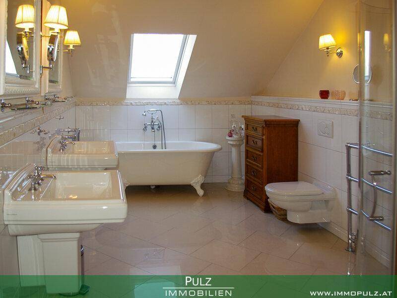 Geräumiges Badezimmer mit freistehender Badewanne, Doppelwaschbecken und Dachfenster.