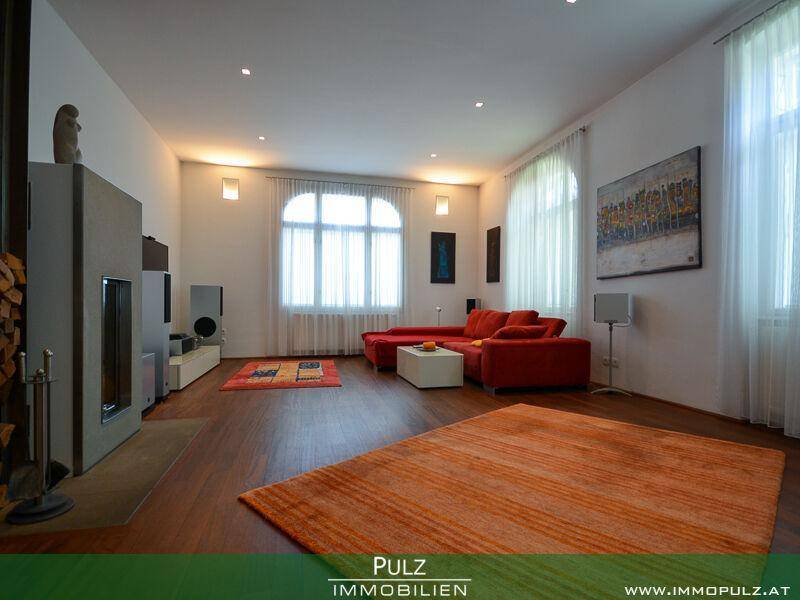 Helles Wohnzimmer mit warmem Holzboden, rotem Sofa und einem modernen Kamin.