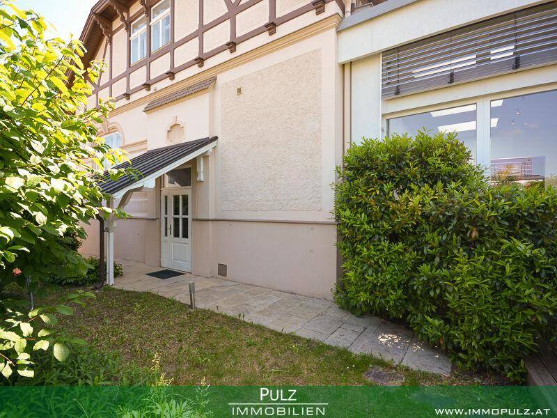 Seitlicher Eingangsbereich des Hauses mit gepflegtem Rasen und einem Steinweg.