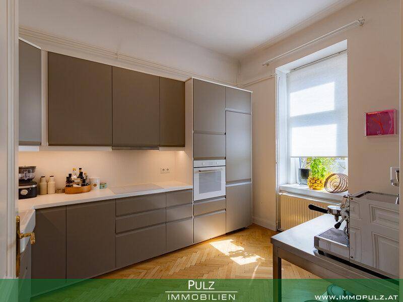 Moderne Küche mit braunen Schränken, weißer Arbeitsplatte und Fenster.