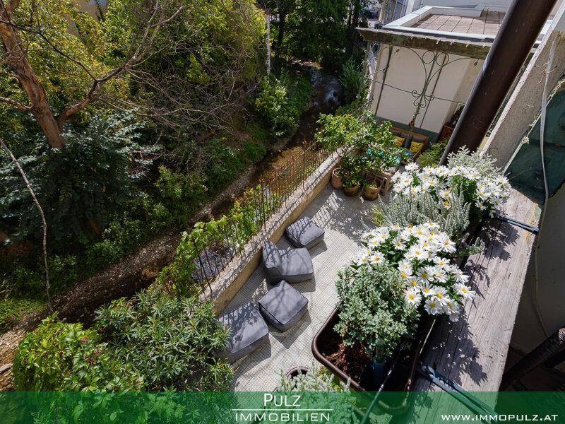 Kleiner Balkon mit Blumenkästen und Blick auf den grünen Innenhof.