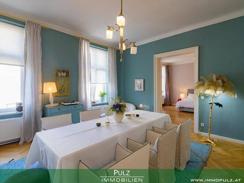 Elegantes Esszimmer mit Parkettboden, blau gestrichenen Wänden und Kronleuchter.