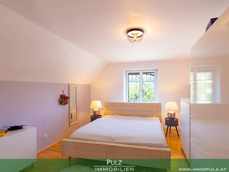 Gemütliches Schlafzimmer mit Dachschräge, Doppelbett und Blick ins Grüne.