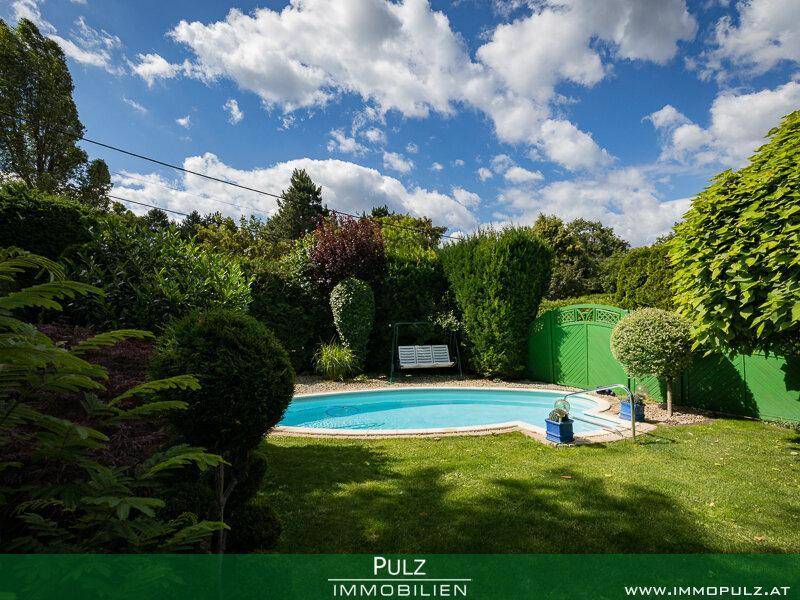 Gepflegter Garten mit ovalem Pool, Rasenfläche und hohen Hecken für Privatsphäre.