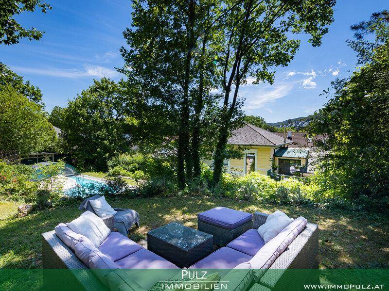 Idyllischer Garten mit bequemen Loungemöbeln, Blick auf den Pool und das Haus im Grünen.