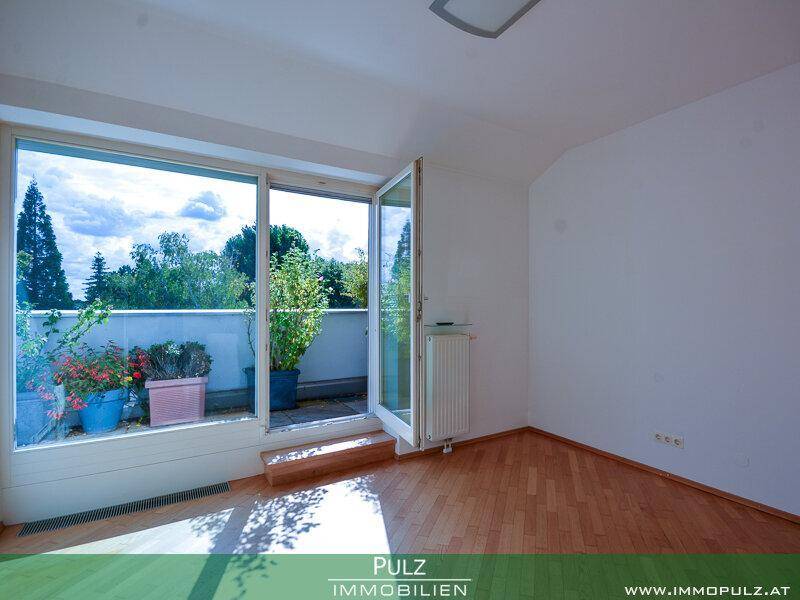 Schlafzimmer mit Holzboden, großen Fenstern und direktem Zugang zur Außenterrasse.