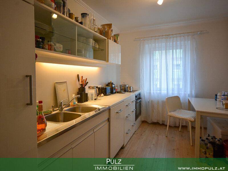 Funktionale Küche mit weißen Schränken, Doppelspüle und Fenster für natürliches Licht.
