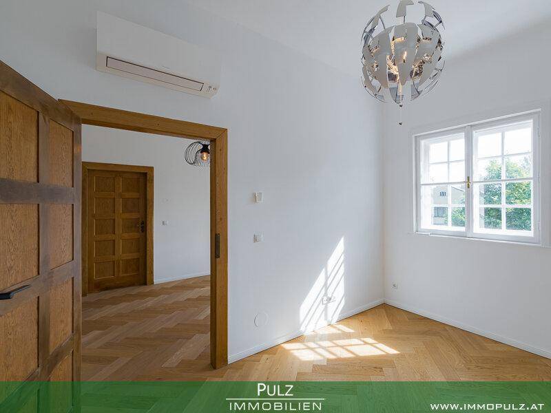 Helles Schlafzimmer mit Parkettboden, Holztüren und Klimaanlage.