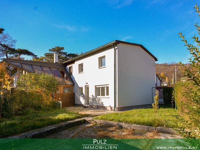 Rückansicht des Hauses mit Wintergarten-Anbau und weitläufigem Gartenbereich.