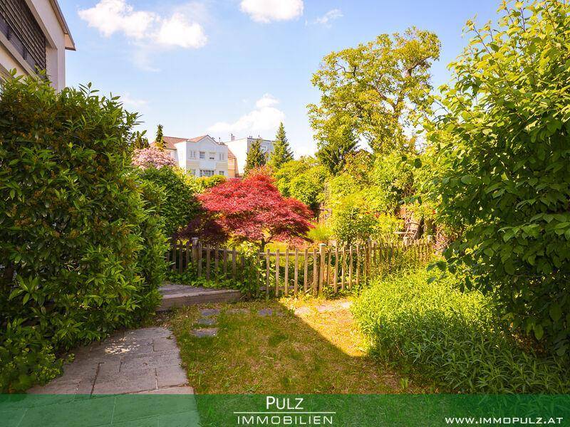 Weitläufiger Garten mit verschiedenen Pflanzen, einem Holzzaun und Blick auf die Nachbarschaft.