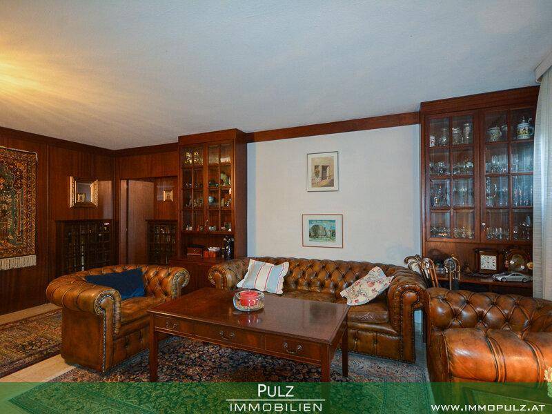 Klassisches Wohnzimmer mit Ledersofas, Holztisch und Vitrinen.