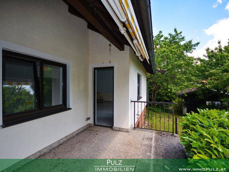 Kleiner gepflasterter Terrassenbereich am Haus mit Zugang zum Garten und Blick ins Grüne.